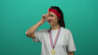 © Krakenimages.com - Woman wearing medal and red headband stands against green wall, expressing displeasure and gesturing with hand, showcasing sports theme with colorful background.