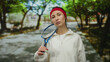 © Krakenimages.com - Young woman with racket in outdoor park setting, showcasing a sporty and determined expression, surrounded by greenery and vibrant natural atmosphere, ready for a sports activity.