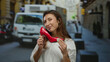 © Krakenimages.com - Woman holding red shoe on city street with yellow taxi and people in background, showcasing urban fashion amidst bustling city life during daytime.
