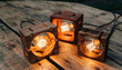 © Kiki - Three handcrafted wooden lamps with illuminated bulbs resting on a wooden surface.