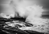 Ocean wave crashing on rocks in black and white dramatic seascape shot