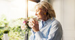 © peopleimages.com - Coffee, dreaming and senior woman by window in home for reflection, memory or thinking in morning. Cappuccino, nostalgia and elderly female person drinking warm beverage for retirement in apartment.