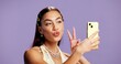 © Lawrenson25/peopleimages.com - Beauty, peace sign and selfie with influencer woman in studio for product review on social media. App, haircare and pout of gen z content creator isolated on purple background for post or update