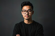 © Viktor - Portrait of young Asian man in black attire wearing eyeglasses. Male with stylish hair and subtle smile against dark grey background. Confident business look.
