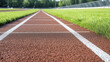 © ธีรเชษฐ์ ชิณวงศ์ - Close up view of running track with focus textured surface and white lane markings, evoking sense of athleticism