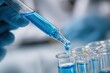 © Iftikhar alam - Closeup of hands expertly dropping blue fluid from a dropper into multiple test tubes on a laboratory table filled with scientific equipment