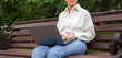© satura_ - Mature woman using laptop while sitting on wooden bench in green park. Banner with copy space and empty place for advertising. Balance, flexibility, and outdoor productivity in remote work lifestyle.