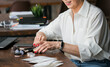 © satura_ - Mature woman organizing cosmetics mineral powder on wooden desk near laptop. Beauty, self-care, and balance between work and personal time in lifestyle.