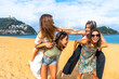 © unai - Friends enjoying piggyback fun on san sebastian beach