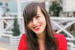 © satura_ - Smiling woman in red polka dot dress outdoors at cafe terrace. Positivity, beauty, and joyful modern lifestyle.
