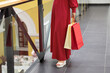 © satura_ - Woman in red polka dot dress holding shopping bags in modern mall. Fashion, retail lifestyle, and consumer culture.