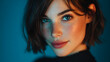 © Selvam - Woman face smiling in a blue studio wearing a black top and casual hair parted bob style portrait; serenity confidence warmth harmony.