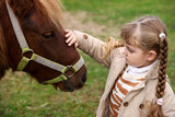 Equine assisted therapy. Little girl with beautiful pony in countryside. Lovely domesticated pet