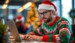 © WOWA - Festive bearded man wearing santa hat working on laptop in cozy office environment during holiday season