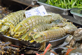 A vibrant display of fresh mantis shrimp, ready for sale at a bustling night market in Bangkok's Chinatown. These popular crustaceans are a common delicacy in Asian cuisine.