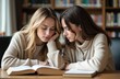© starush - Two young women studying together at a library table with books and focused expressions