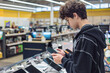 © Светлана Мищенко - Teenager Choosing a Tablet in Electronics Store – Young Customer Testing Digital Devices, Tech Shopping and Consumer Behavior. gadget choice, digital lifestyle, retail shopping experience. Gen Z