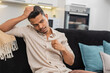 © Andrii Iemelianenko - Indian man at home sits quiet after rough day feels stress holds head breathes slow and looks down. Arabian guy on sofa stays still with low mood stares ahead controls breath and waits for calm focus
