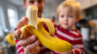 © Nat - A man holding a banana in front of a child