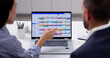© Andrey Popov - Busy Professionals Planning Meeting Using Online Calendar