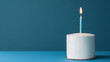 © A2Z AI  - Minimalist birthday celebration with a single-layer cake, adorned with a blue and white striped candle, lit on a matching blue surface, setting a festive yet simple scene.
