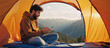 © STBSTD - Digital Nomad's Retreat: A bearded person, immersed in their mobile phone, finds solace in the heart of nature, laptop near, from a warm orange tent, while mountain range.