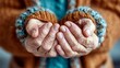 © hardhan - Elderly hands are cupped together, showing wrinkles and worn skin, while wearing a warm knitted sweater and cuffs.