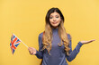 © luismolinero - Young Russian girl holding an United Kingdom flag isolated on yellow background having doubts while raising hands