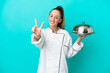 © luismolinero - Young caucasian chef woman with tray isolated on blue background smiling and showing victory sign