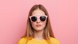 © Marius - Stylish young woman wearing pink sunglasses and yellow top, radiating confidence and modern fashion appeal against a vibrant pink backdrop.