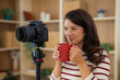 © Dexon Dee - Woman drinking coffee while recording online video content