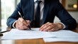 © Fotograf - A business professional signing a contract or agreement with a pen, useful for office and corporate themes