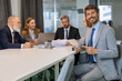© ty - Portrait of adult businessman sitting at his desk in the office and smiling looking at camera