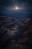 Majestic full moon illuminates vast canyon landscape with winding river below under dramatic nighttime sky