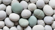 © mmizan - A close up overhead view of smooth rounded pebbles with a mix of white and subtle green hues creating a calming natural texture