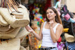 © JackF - Young girl choosing fashionable straw bag with interest at street market