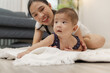 © kamiphotos - A loving mother spends quality time with her baby, helping him practice tummy time, rolling, and sitting up. These tender moments reflect family bonding, care, and child development at home.
