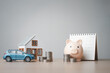 © Garun Studios - personal, assets, finance, savings, house, car, investment, mortgage, insurance, House model, car, and piggy bank with coins on table, representing personal finance, savings, and investment planning.