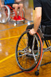 © Austockphoto - vertical image focused on one wheel with two wheelchairs o a basketball court