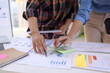 © SOMKID - Business person hands working with business financial graph data and marketing plan at desk in office, Business people meeting explaining and business concept.