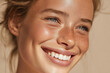 © Enrique - a smiling young woman with glowing natural skin, minimal makeup, neutral beige background, soft daylight, skincare concept