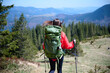 © Василь Івасюк - Back view of female hiker in red raincoat and backpack trekking in mountain valley. Adventure, nature, and travel lifestyle in the wilderness.