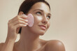 © Buyanskyy Production - Smiling Woman Using Pink Gua Sha Stone for Facial Skincare Routine