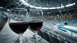 © Tanu - Glasses of red wine on a ledge overlooking an empty arena as evening lights illuminate the venue