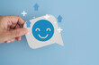 © Ratana21 - hand hold real white speech bubble paper cut with happy smile face and mental health recovery emotional healing, positivity, self care, and personal growth on blue background