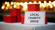 © Arra Vais - Local charity drive sign next to red donation boxes on table with glowing lights. Local charity drive event is displayed on table in support of fundraising initiatives.
