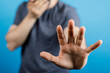© vegefox.com - A person raising his hand in a stopping gesture.  The man is showing a hand to signal stop or no entry. Shot on a plain blue background.