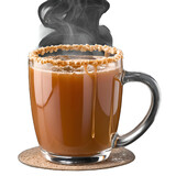 A clear glass mug filled with a brown liquid topped with nuts and steam on a cork coaster