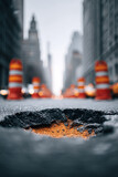 Urban decay meets gritty beauty. Pothole in city street, construction cones signal hazard. Use for infrastructure, repair, urban issues, or metaphorical challenge concepts.