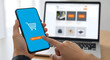 © AH Project - Seamless online shopping experience with a finger tapping 'Add to Cart' on a smartphone, laptop displaying e-commerce site in background